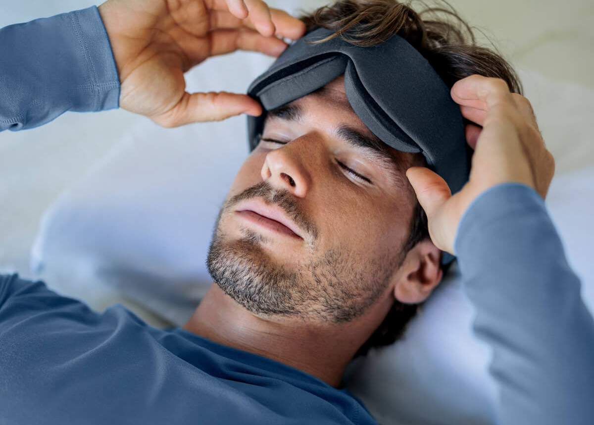 Man lying in bed wearing a sleep mask