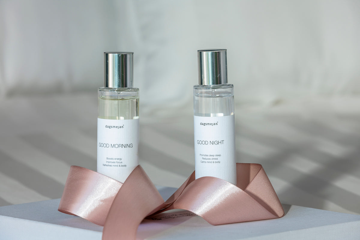 Two bottles of 'Good Morning' and 'Good Night' products on a pink stand with a neutral background.